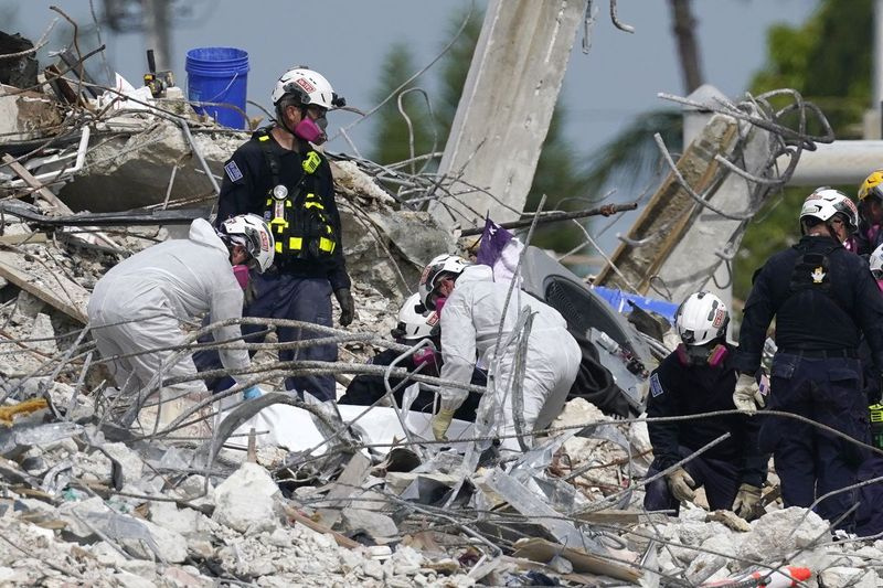 Pekerja penyelamat mengendalikan tarp yang mengandungi mayat yang ditemui di tapak bangunan kondo Champlain Towers South yang runtuh, Isnin, 5 Julai 2021, di Surfside, Fla. Struktur selebihnya telah dirobohkan pada Ahad, yang sebahagiannya runtuh pada 24 Jun. Ramai orang masih tidak dapat dikesan .
