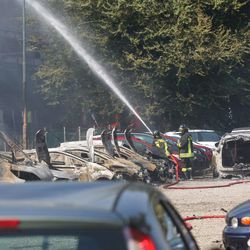 Ватрогасац прска воду међу угљенисана возила испод аутопута након што је експлодирала камион цистерна.| Гиоргио Бенвенути/АНСА преко АП