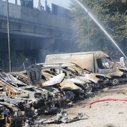 Ватрогасац прска водом угљенисана возила испод аутопута након што је експлодирала камион цистерна. | Гиоргио Бенвенути/АНСА преко АП
