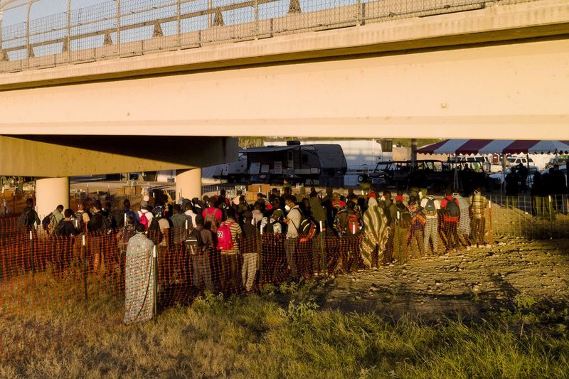 Penktadienį, 2021 m. rugsėjo 24 d., Del Rio mieste, Teksase, migrantai, daugelis iš Haičio, laukia eilėse, kad galėtų įsėsti į autobusus po Del Rio tarptautiniu tiltu.