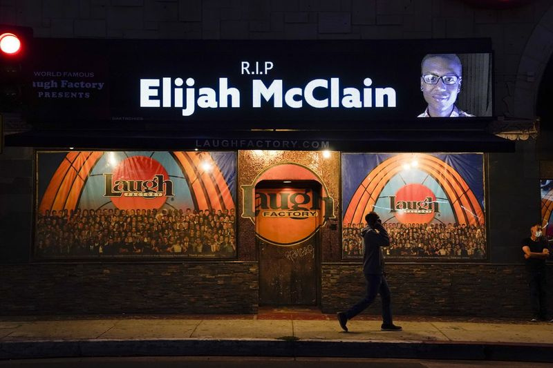 En esta foto de archivo del 24 de agosto de 2020, un hombre pasa junto a una pantalla que muestra una imagen de Elijah McClain afuera de Laugh Factory durante una vigilia con velas para McClain en Los Ángeles. El fiscal general de Colorado dijo el miércoles 1 de septiembre de 2021 que un gran jurado acusó formalmente a tres oficiales y dos paramédicos por la muerte de Elijah McClain, un hombre negro al que le pusieron un estrangulamiento y le inyectaron un poderoso sedante hace dos años en los suburbios de Denver.