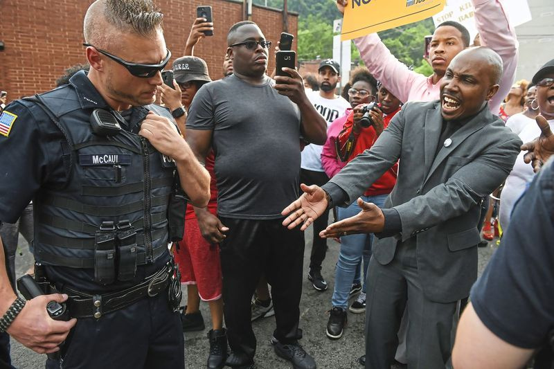 Leonard Hammonds II. aus Penn Hills (rechts) weist darauf hin, dass ein Polizist von Turtle Creek während einer Kundgebung in East Pittsburgh, Pennsylvania, am 20. Juni 2018 bei einer Protestkundgebung gegen die Erschießung von Antwon Rose seine Hand an seiner Waffe hat von einem East Pittsburgh Po