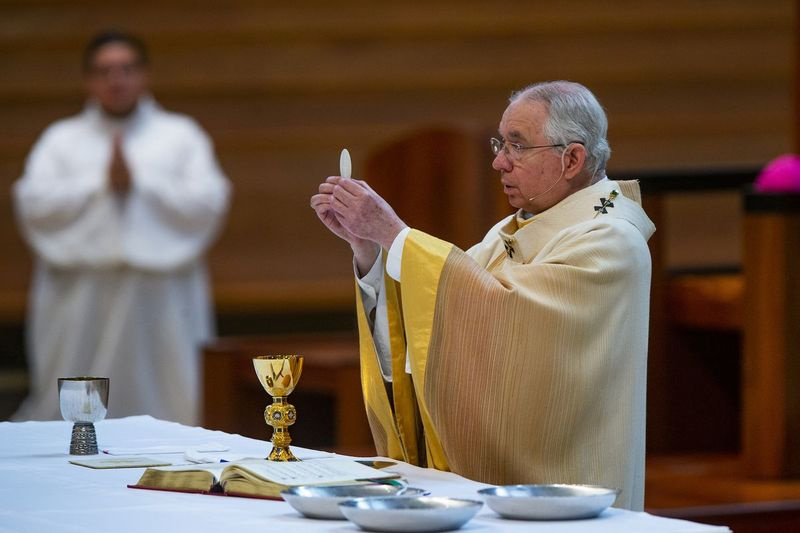 El arzobispo José H. Gómez sostiene una hostia de comunión mientras celebra la Solemnidad de la Santísima Trinidad, una misa con los feligreses presentes en la Catedral de Nuestra Señora de los Ángeles en el centro de Los Ángeles.