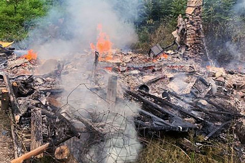 Rök stiger upp den 4 augusti från de brända resterna av en stuga i Canterbury, NH, bebodd av 81-årige David River Dave Lidstone, som i 27 år har bott i skogen i New Hampshire längs Merrimack River i solpaneler. stuga.