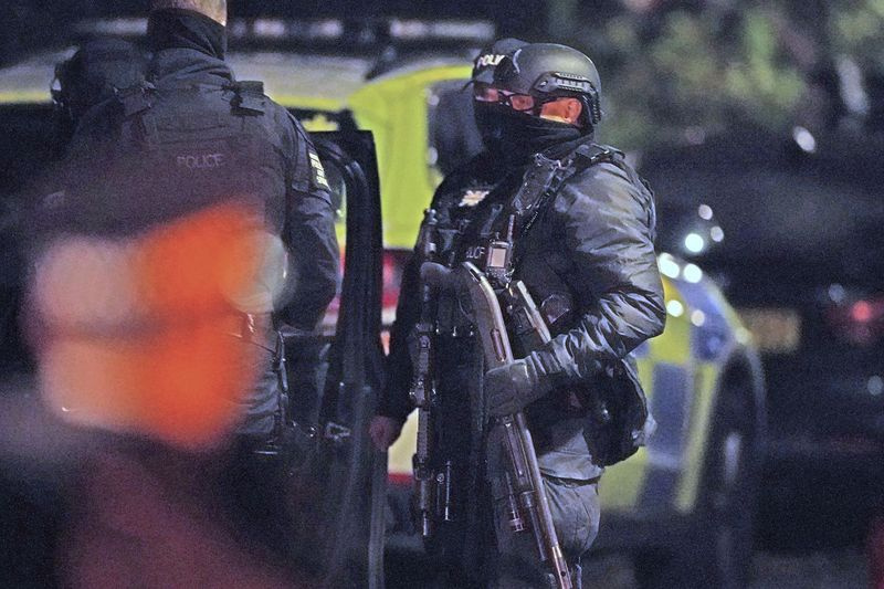 En beväpnad polis håller i ett brytande hagelgevär, som användes för att spränga gångjärnen från en dörr, på en adress på Rutland Avenue i Sefton Park, efter en explosion på Liverpool Women