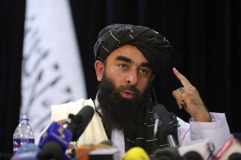Taliban karoga priekšā Taliban pārstāvis Zabihullah Mujahid uzstājas savā pirmajā preses konferencē Kabulā, Afganistānā, otrdien, 2021. gada 17. augustā. Mudžahids gadiem ilgi bija ēnas personība, kas sniedza paziņojumus kaujinieku vārdā. Mudžahids otrdien solīja, ka talibi ievēros sieviešu tiesības, piedos tiem, kas tām pretojās, un nodrošinās drošu Afganistānu, lai pārliecinātu pasaules lielvaras un bailīgos iedzīvotājus, ka tās ir mainījušās.