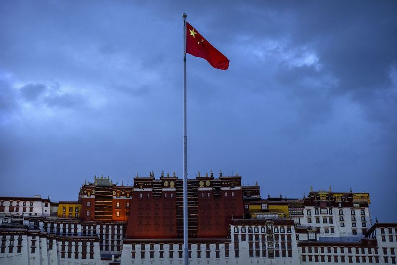 Čínská vlajka vlaje na náměstí poblíž paláce Potala ve Lhase v západočínské Tibetské autonomní oblasti, úterý 1. června 2021, jak bylo vidět během vládou organizované návštěvy zahraničních novinářů. Zdá se, že taktika vysokého tlaku, kterou používá čínská vládnoucí komunistická strana, má úspěch v oddělování Tibeťanů od jejich tradiční buddhistické kultury a vlivu dalajlámy.