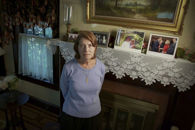 Margot Eckertová stojí u vystavených obrázků svého švagra Seana Rooneyho a sestry Beverly Eckertové ve svém domě ve Springfieldu, Massachusetts. Rooney byl zabit 11. září při práci ve své kanceláři v South Tower. Jeho manželka Beverly Eckert zemřela v roce 2009 při letecké havárii.