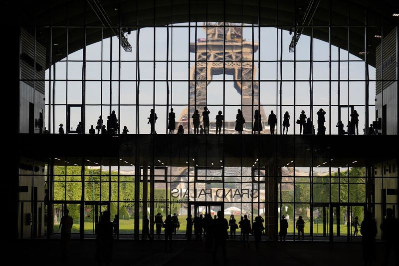 Na této souborové fotografii ve středu 9. června 2021 se návštěvníci shromáždili během prezentační návštěvy Grand Palais Ephemere s Eiffelovou věží v pozadí v Paříži.