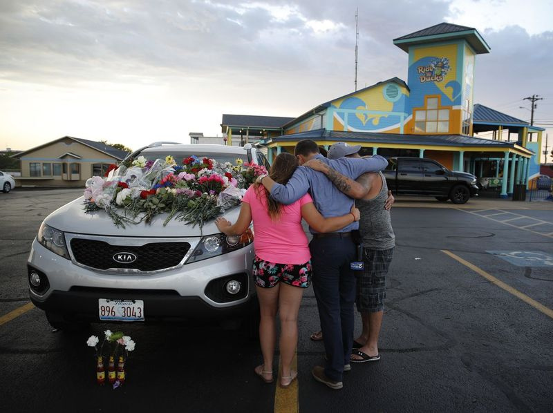 Pessoas oram por um carro que se acredita pertencer a uma vítima do acidente de barco de quinta-feira antes de uma vigília à luz de velas no estacionamento da Ride the Ducks sexta-feira, 20 de julho de 2018, em Branson, Missouri. Um dos barcos de patos da empresa virou na noite de quinta-feira, resultando em o