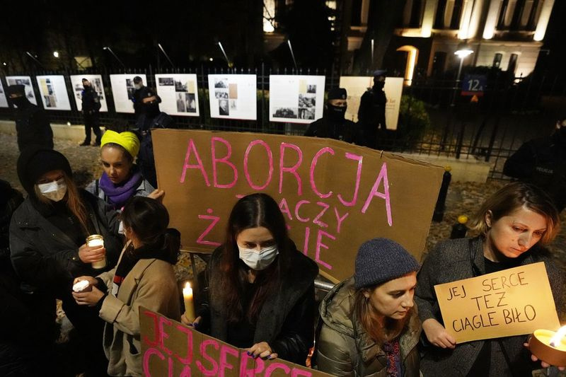 La gente en Varsovia sostiene un cartel pidiendo la legalización del aborto y colocan velas en homenaje a una mujer que murió en la semana 22 de embarazo.