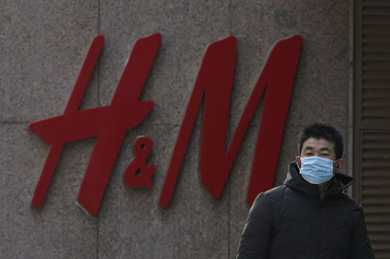 En man som bär en ansiktsmask går förbi ett svenskt modemärke H&M-butik i Peking, torsdagen den 25 mars 2021.