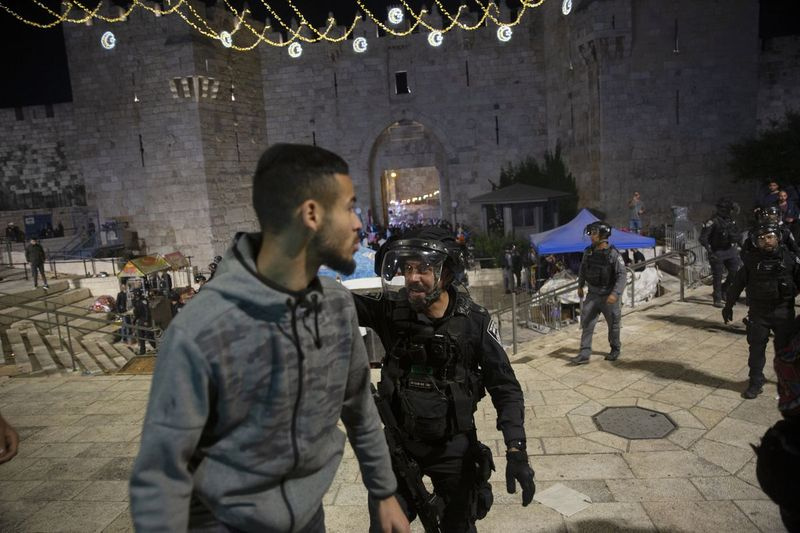 Piektdien, 2021. gada 7. maijā, Izraēlas policists kliedz uz palestīniešu vīrieti, lai tas atstāj Damaskas vārtus uz Jeruzalemes vecpilsētu pēc sadursmēm Al-Aksas mošejas kompleksā, piektdien, 2021. gada 7. maijā. Piektdienas vakarā palestīniešu dievlūdzēji sadūrās ar Izraēlas policiju svētajā vietā. musulmaņi un ebreji nedēļu ilgas vardarbības saasināšanās laikā Jeruzalemē, kas atbalsojusies visā reģionā.