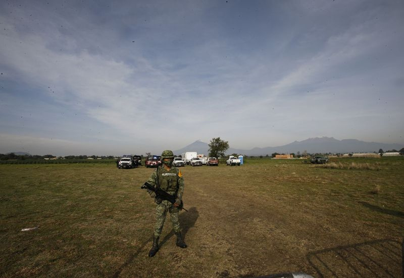 En mexikansk soldat står på vakt innanför en säkerhetsperimeter runt ett vattenfyllt slukhål i Zacatepec, i utkanten av Puebla, Mexiko.