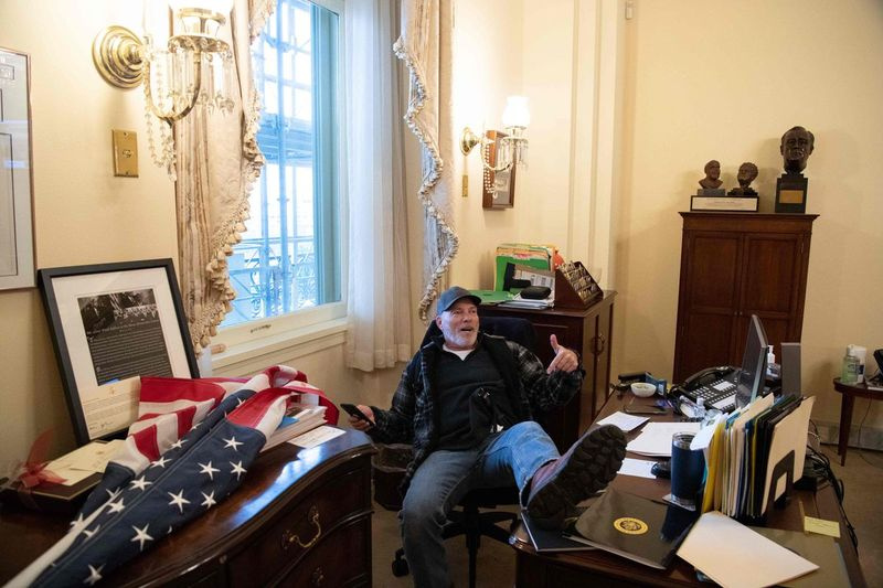 Richard Barnett, en tilhenger av USAs president Donald Trump, sitter på kontoret til den amerikanske presidenten i huset Nancy Pelosi mens han protesterer inne i den amerikanske hovedstaden i Washington, DC, 6. januar 2021.