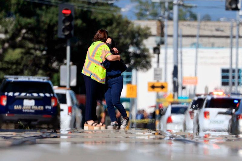 Divi cilvēki apskaujas Younger Avenue ārpus apšaudes vietas Sanhosē, Kalifornijā, trešdien, 2021. gada 26. maijā.