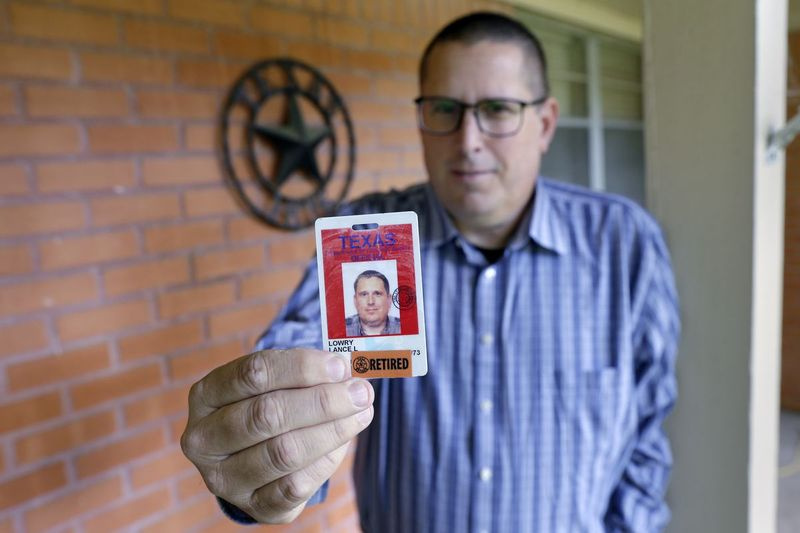 Lance Lowry ukazuje identifikační odznak, který nosil, než odešel do důchodu jako důstojník nápravných zařízení ve státní věznici v Texasu. Lowry, z Huntsville, Texas. byl 20 let korekčním důstojníkem, ale byl znechucený, když viděl, jak přátelé a spolupracovníci umírali na COVID-19, a cítil, že se mu ze strany jeho šéfů dostává mizivé podpory. Letos v létě opustil vězeňský systém kvůli práci v dálkové kamionové dopravě.