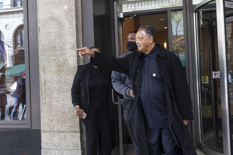 Jackson je imel povoj na glavi, a je dejal, da se v četrtek počuti fantastično. Rev. Jesse Jackson pozdravlja novinarja po odhodu s Pravne fakultete Univerze Illinois v Chicagu, četrtek, 4. novembra 2021.