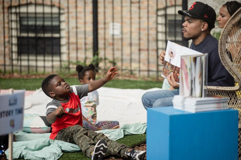 Josiah Wilcher mengangkat tangannya manakala Chance the Rapper membaca buku semasa acara Chance and Bri