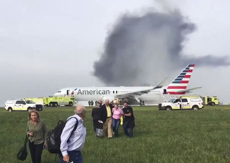 Nesta foto fornecida pelo passageiro Jose Castillo, outros passageiros se afastam de um jato em chamas da American Airlines que abortou a decolagem e pegou fogo na pista do Aeroporto Internacional O