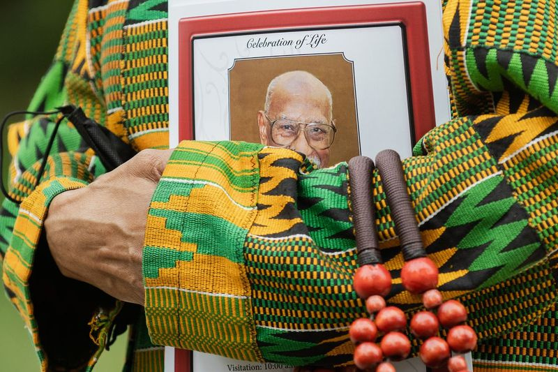ティミュエルブラックの葬式の出席者は、先週亡くなった102歳の歴史家で活動家であるブラックの葬式が行われた、ハイドパーク地区のファーストユニタリアン教会の外でブラックの写真が描かれたプログラムを開催します。 2021年10月22日朝。