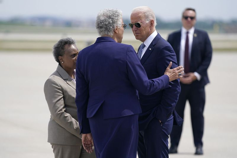 Președintele Joe Biden este întâmpinat de președintele consiliului de administrație al comitatului Cook, Toni Preckwinkle, în centru, și de primarul din Chicago, Lori Lightfoot, în stânga, când sosește miercuri pe Aeroportul Internațional O’Hare.