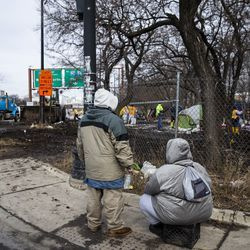Inimesed istuvad teepervel ja vaatavad, kuidas linna tänavate ja kanalisatsiooni osakonna töötajad puhastavad esmaspäeva hommikul, 10. veebruaril 2020 South Desplaines Streeti ja West Roosevelt Roadi lähedal asuvat kodutute laagrit.