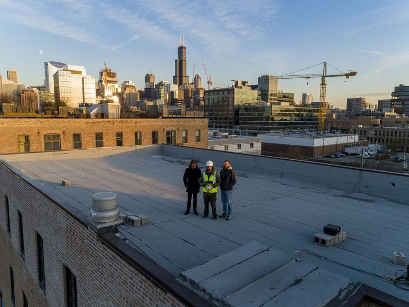 Mede-oprichters van Helios Visions (van links) Ted Parisot, Tyler Gibson en Gavin Gin gefotografeerd door een drone bovenop hun kantoorgebouw in West Town.