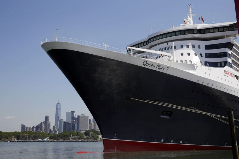 Die Skyline von New York City erscheint hinter dem Ozeandampfer Queen Mary 2, als sie am Mittwoch, den 6. Juli 2016, in ihrem Heimathafen am Brooklyn Cruise Terminal in New York angedockt ist. | AP Foto/Richard Drew
