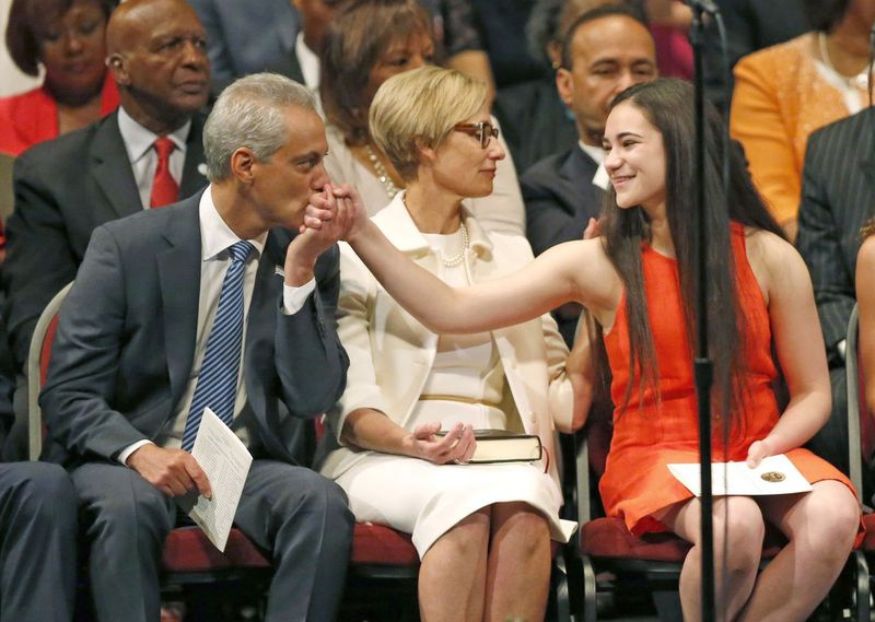 O prefeito de Chicago, Rahm Emanuel (à esquerda) beija a mão de sua filha, Leah, enquanto sua esposa Amy Rule se senta entre eles durante sua posse em 2015 para um segundo mandato. | Associated Press
