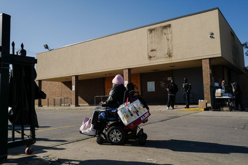 Ein Bewohner einer Gemeinde in einem Rollstuhl betritt am Samstagmorgen, den 6. November 2021, eine Lebensmittelverteilungsveranstaltung vor dem geschlossenen Aldi in der W. Madison St. 3835 im Stadtteil West Garfield Park. Die Veranstaltung fand als Reaktion auf die abrupte Schließung des Lebensmittelgeschäft im Oktober.