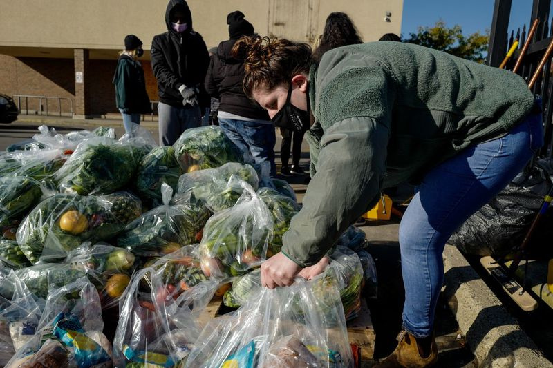Ein Freiwilliger trägt während einer Lebensmittelverteilungsveranstaltung außerhalb des geschlossenen Aldi in 3835 W. Madison St. im Stadtteil West Garfield Park am Samstagmorgen, 6. November 2021, Tüten mit Lebensmitteln.