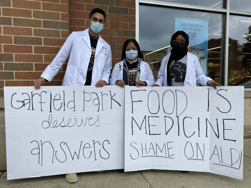 Von links posieren die Rush Medical College-Studenten Rohan Luhar, Marissa Pharos und Sadiyya Ingawa mit handgefertigten Schildern vor dem Aldi-Hauptsitz in der California Ave. und Granville Ave. Donnerstag, 28. Oktober 2021