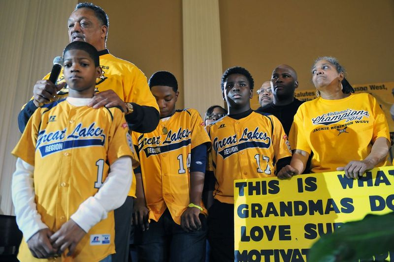 Rev. Jesse Jackson fala por (da esquerda) D.J. Butler, Brandon Green (apanhador / arremessador) e Joshua Houston (arremessador) do time Jackie Robinson West Little League em 14 de fevereiro de 2015, que perdeu seu título de campeão da Little League dos EUA.
