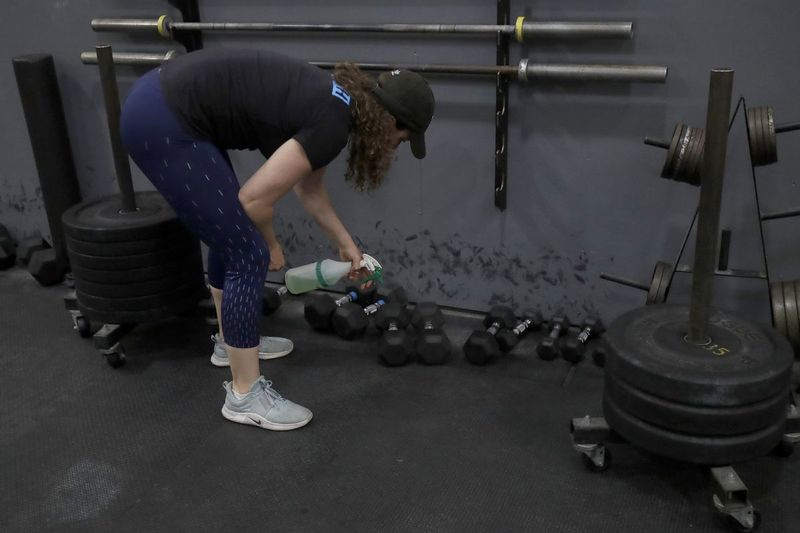 W piątek, 24 kwietnia 2020 r., zdjęcie pliku, Alexis Garrod, partner i główny trener CrossFit Potrero Hill, czyści sprzęt do treningu siłowego w pustej sali gimnastycznej, która została zamknięta dla schronienia w celu złożenia zamówień na obawy związane z COVID-19 w San Francisco. Reebok twierdzi, że zerwał kontakty z dyrektorem naczelnym i założycielem CrossFit, powołując się na nazwisko George