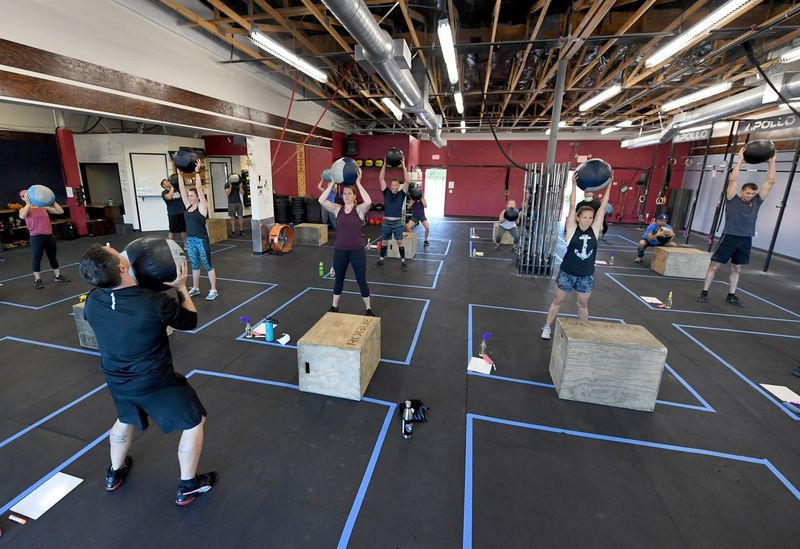 Ludzie ćwiczą w boksach o wymiarach 7 na 7 stóp na dystansach społecznych w CrossFit Apollo w Las Vegas, które zostało otwarte w zeszłym miesiącu po raz pierwszy od zamknięcia 17 marca z powodu ogólnostanowego zamknięcia z powodu pandemii koronawirusa (COVID-19).