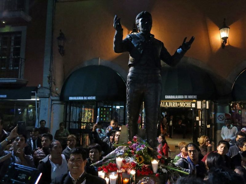 Le persone si riuniscono intorno a una statua raffigurante il cantautore e cantante superstar messicano Juan Gabriel nella piazza Garibaldi di Città del Messico, domenica 28 agosto 2016. L