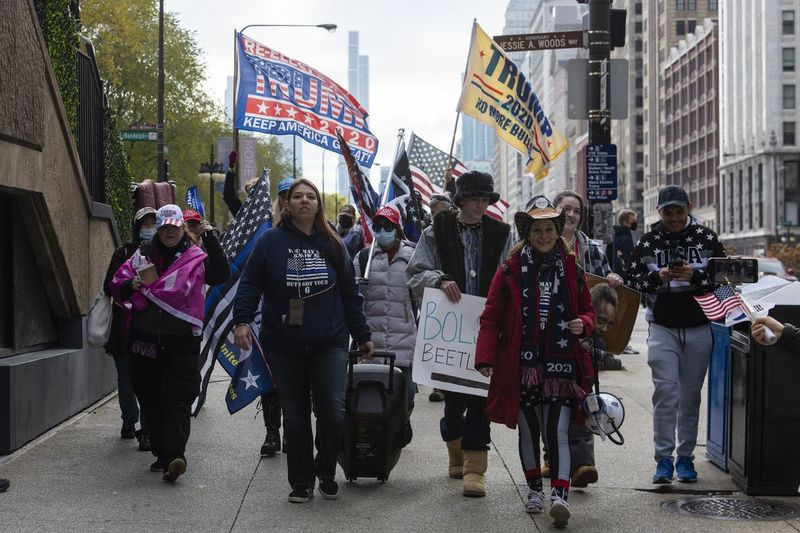 Ashley Ramos (linksvoor) en een groep Stop the Steal-demonstranten lopen richting Trump Tower na protest in Millennium Park, donderdag 26 november 2020.