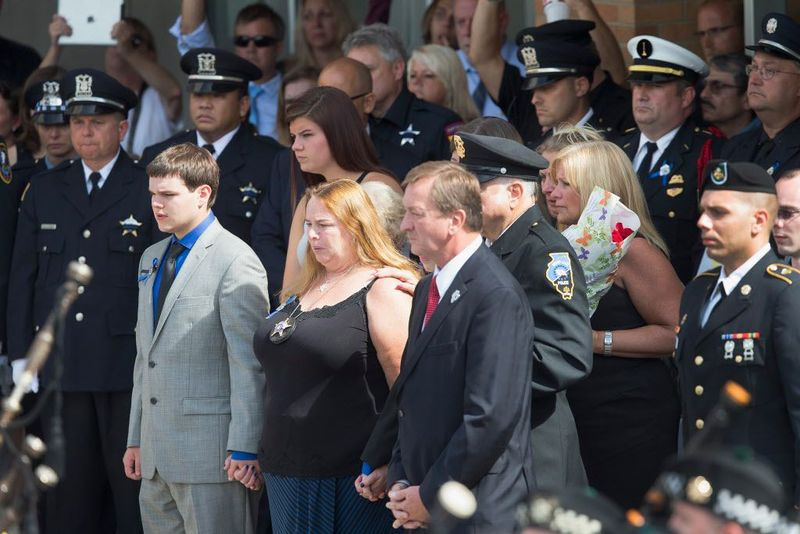 Mel Gliniewicz (i midten), hustruen til den dræbte Fox Lake politiløjtnant Joe Gliniewicz, forlader sin mands begravelsestjeneste på Antioch Community High School på mandag. | Scott Olson/Getty Images