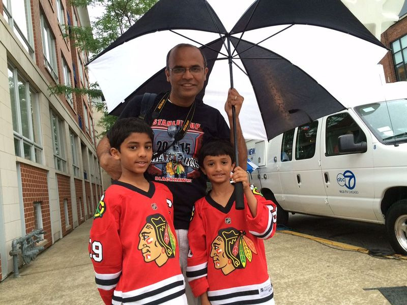 Mehul Patel, 39, e seus filhos Kunal, 7, e Kushal, 9, todos de Elgin, tentam ficar secos perto do início do percurso do desfile. | Stefano Esposito / Sun-Times