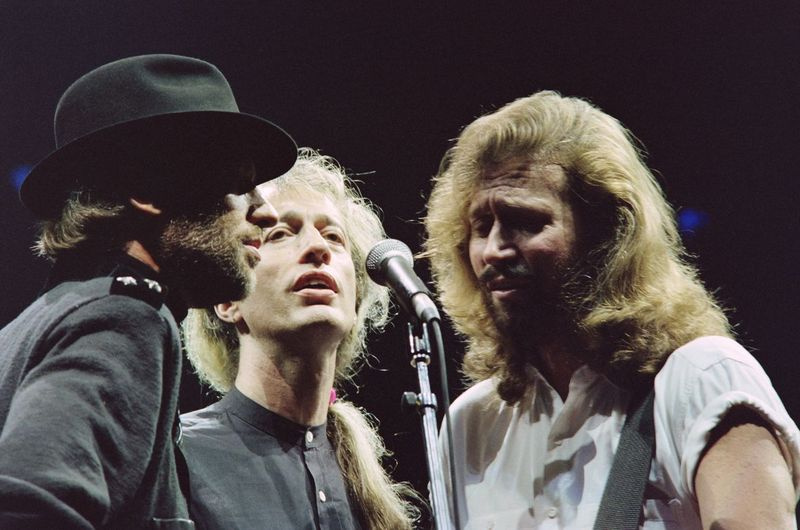 Bee Gees — Robin Gibb (i midten), flankeret af sine to brødre Maurice (til venstre) og Barry, under en koncert i Paris Bercy den 23. juni 1991. | (Foto BERTRAND GUAY/AFP/GettyImages