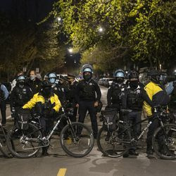 Policjanci z Chicago blokują drogę protestującym, którzy próbują zbliżyć się do domu burmistrza Lori Lightfoot w dzielnicy Logan Square w Chicago, piątek, 16 kwietnia 2021 r.