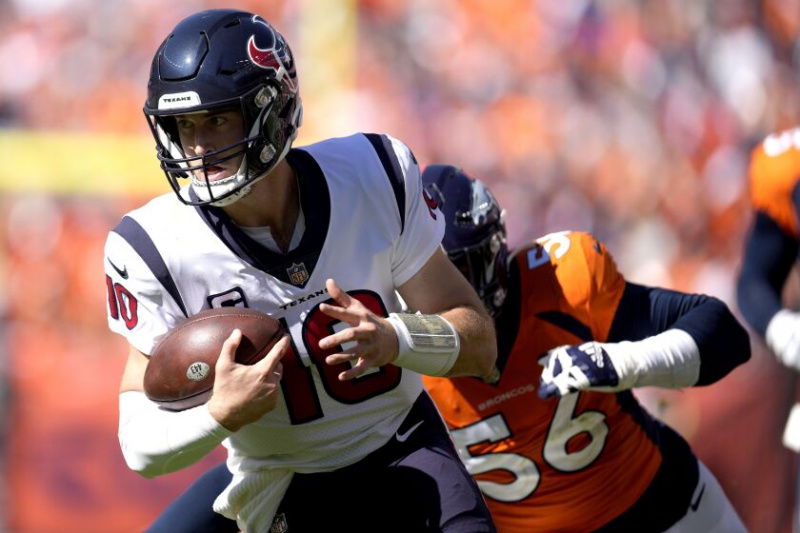   Rozgrywający Houston Texans, Davis Mills (10), walczy, gdy zawodnik drużyny Denver Broncos, Baron Browning (56), ściga się w pierwszej połowie niedzielnego meczu.