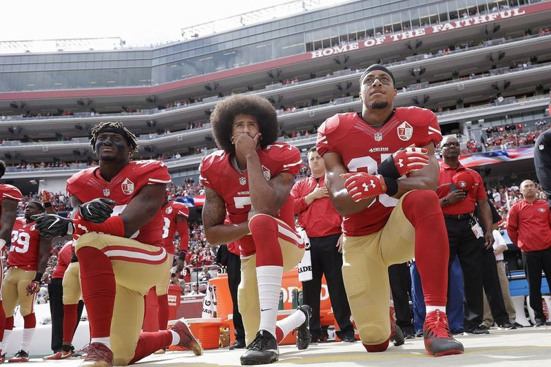 Na snímke z roku 2016 Eli Harold, Colin Kaepernick a Eric Reid kľačia počas štátnej hymny.