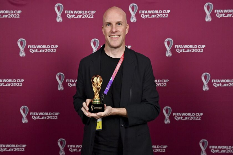   Grant Wahl tersenyum sambil memegang trofi replika Piala Dunia semasa majlis anugerah di Doha, Qatar pada 29 Nov.