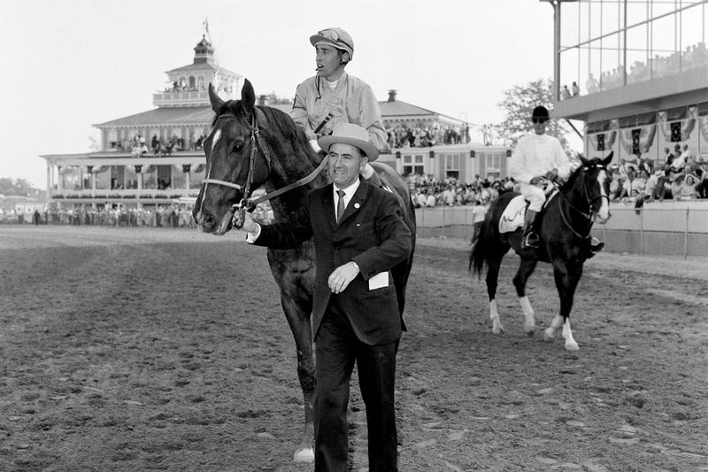 Trener Virgil Raines prowadzi greckiego Moneya i dżokeja Johna Rotza do kręgu zwycięzców po wygraniu 85. Preakness Stakes 19 maja 1962 r., zdjęcie pliku. Rotz, Hall of Famer, zmarł w wieku 86 lat.