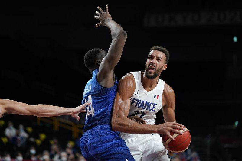 De Franse Rudy Gobert rijdt langs de Amerikaanse Draymond Green, links, tijdens de wedstrijd van zondag op de Olympische Spelen in Tokio.