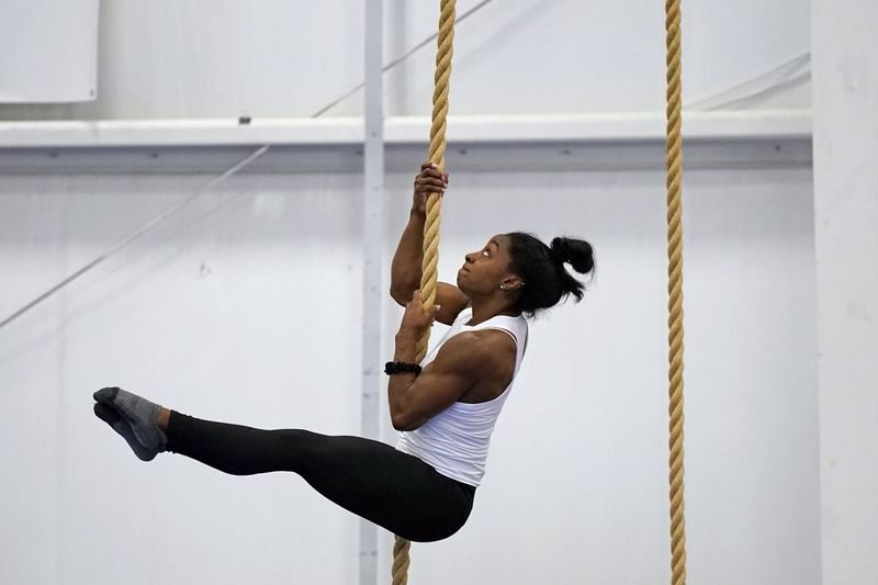 La ginnasta campionessa olimpica Simone Biles si arrampica su una corda durante una sessione di allenamento.