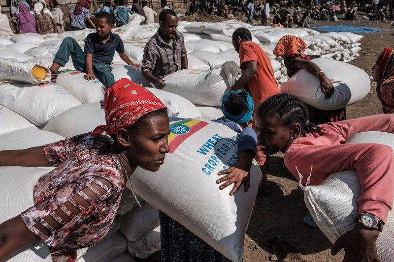 Dalam foto fail dari Disember 2020 ini, wanita membawa guni gandum semasa pengedaran makanan di bandar Alamata, Ethiopia.