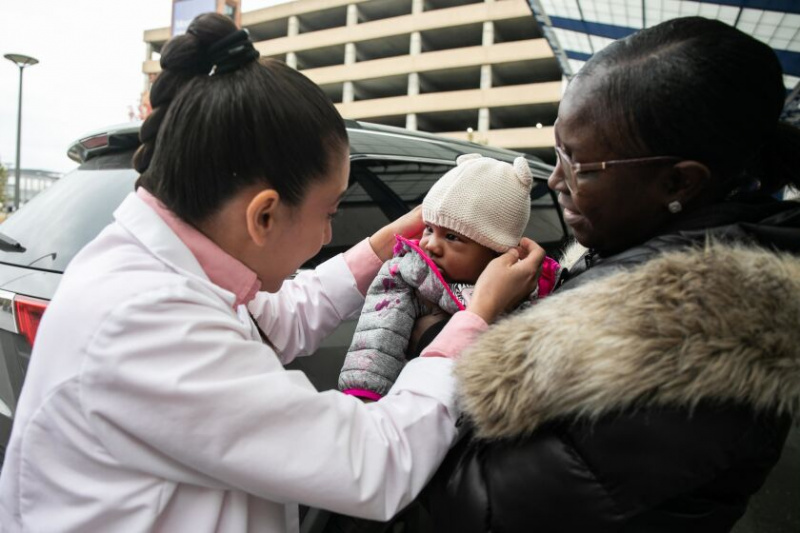   Alejandra Chavez, een gezondheidswerker voor de vrouwen- en kinderafdeling van het Mount Sinai Hospital, begroet de vier maanden oude Antoinette Gerald terwijl haar moeder Latashia Cannon, 35, haar vasthoudt na het ontvangen van gratis luiers buiten het Mount Sinai Hospital, donderdag 10 oktober. 20, 2022. De luierbank van de berg Sinaï geeft een voorraad luiers voor zes maanden weg aan moeders die elke donderdag in het ziekenhuis bevallen.